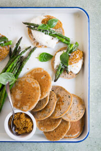 Blini met asperges, burrata en mosterdkaviaar op een serveerplank