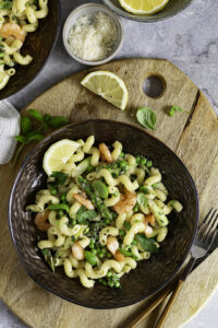 Pasta met asperges en scampi op bord met citroen en basilicumblaadjes